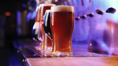 Bira bardaklarının yakın plan görüntüsü, koyu ve neon biralı. Seçici odaklanma. Soğuk, soğuk bir içecek. İçecek bir şeyler. Bar, bar atmosferi. İçki, parti, tat, rahatlama kavramı. Ad