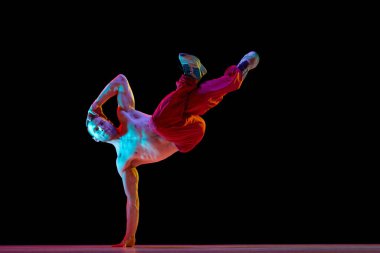 Bir el standı. Gömleksiz, kaslı, sportif genç adam küçümseme, neon ışıkta siyah stüdyonun arka planına karşı breakdance. Sanat, sokak dansı, moda, gençlik, hobi, dinamik, reklam konsepti
