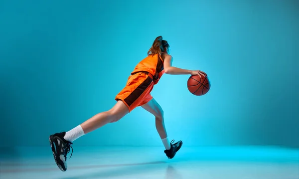 后视镜动态画面中的年轻女孩 篮球运动员在霓虹灯下在蓝色工作室的背景下运球 职业运动 动作和运动 业余爱好 广告的概念 — 图库照片