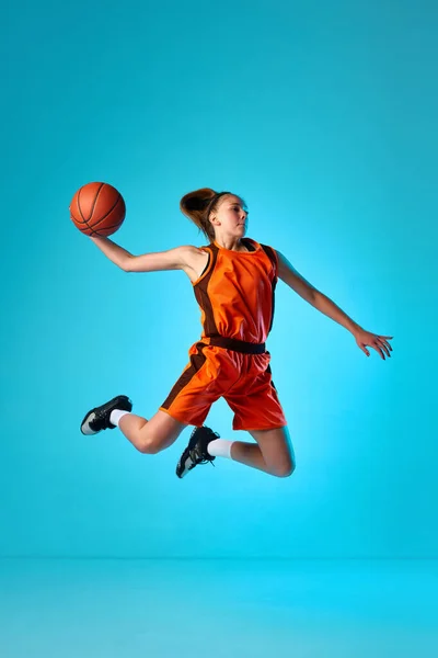 年轻的女孩 篮球运动员在运动 投球在一个跳跃蓝色工作室背景在霓虹灯下 灌篮灌篮 职业运动 动作和运动 业余爱好 广告的概念 — 图库照片