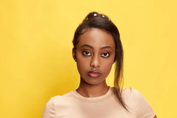 形象美丽的年轻非洲姑娘摆姿势 看着镜头 带着严肃的表情笼罩在黄色的工作室背景上 集中注意力的样子生活方式 人类情感 广告的概念 — 图库照片