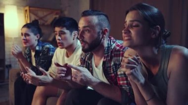 Gençler, evdeki kanepede oturan arkadaşlar ve televizyonda futbol maçı izleyen taraftarlar favori takımı neşelendiriyor. Kazanmak ve kaybetmek. Boş zaman, spor hayranları, arkadaşlık, duygu konsepti.