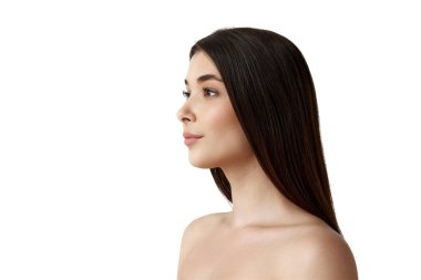 Beyaz stüdyo arka planında düzgün esmer ve pürüzsüz ciltli güzel, narin bir genç kadının portresi. Kadın güzelliği, vücut ve cilt bakımı, kozmetoloji, sağlık, reklam