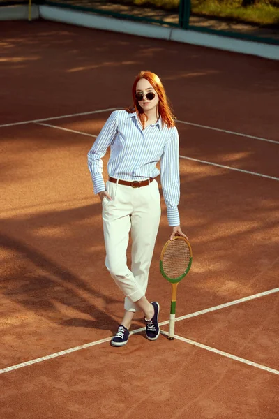 身穿时髦休闲装和太阳镜的红头发美女在露天网球场摆姿势的全景全景照片 积极的生活方式 业余爱好 闲暇时间 广告概念 — 图库照片