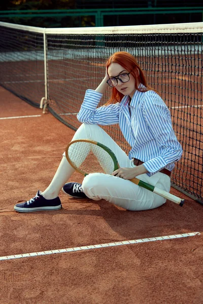 穿着时髦眼镜 穿着休闲装 在露天网球场摆设球拍的漂亮红头发女人的画像 体育概念 积极的生活方式 业余爱好 闲暇时间 — 图库照片