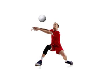 Servis topu. Genç konsantre adam, profesyonel voleybol oyuncusu kırmızı üniformalı beyaz stüdyo arka planına karşı hareket ediyor. Spor anlayışı, aktif yaşam tarzı, sağlık, dinamik, oyun, reklam