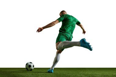 Genç adam, yeşil üniformalı futbolcu hareket halinde, topa vuruyor, antrenman yapıyor, beyaz arka planda oynuyor. Profesyonel spor, eylem, yaşam tarzı, rekabet, hobi, eğitim, reklam kavramı