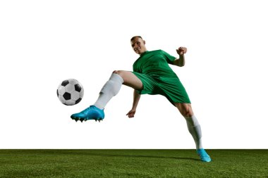 Alt manzara. Rekabetçi adam, yeşil üniformalı futbolcu, bacağı beyaz arka planda topa vuruyor. Profesyonel spor, eylem, yaşam tarzı, rekabet, hobi, eğitim, reklam kavramı