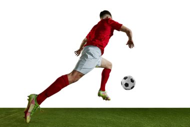 Alttaki görüntüde kırmızı üniformalı genç bir adam var. Futbolcu beyaz arka planda topla sahada koşuyor. Profesyonel spor kavramı, eylem, rekabet, eğitim, reklam
