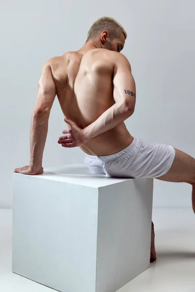 放轻松英俊的年轻人 肌肉发达 赤身裸体 穿着灰色的内裤 背景是灰色的 男性自然美 身体护理 广告等概念 — 图库照片