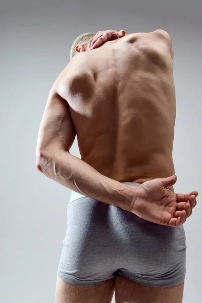 シャツのない 筋肉質の男性の体のリアビュー画像 灰色のスタジオの背景に対する救済 下着姿の若いモデル 男性の自然の美しさの概念 ボディケア スポーツ ファッション — ストック写真