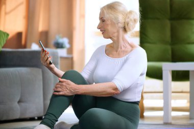 Spor giyim bölümünden güzel bir bayan telefonda eğitim için online spor videoları izliyor. Sportif ve sağlıklı yaşam tarzı kavramı, yaş, vücut bakımı, spor, sağlık.