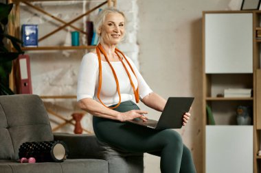 Güzel, hoş, rahat spor giyim bölümünde son sınıf öğrencisi ev eğitimi için dizüstü bilgisayarda spor dersleri arıyor. Spor anlayışı, sağlıklı yaşam tarzı, yaş, vücut bakımı, spor, sağlık.