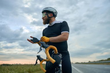 Spor kıyafetli, gözlüklü ve kasklı, arka planda bisikleti olan sportif sakallı bir adamın görüntüsü. Spor, hobi, boş zaman aktivitesi, eğitim, sağlık, hız, dayanıklılık kavramı