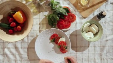 Caprese salata hazırlığı. Erkek elinin tabakta domates, peynir ve fesleğen karıştırdığı en iyi görüntü. Hobi kavramı, aşçılık, yemek hazırlama, tat alma, diyet, sağlıklı yemek, reklam