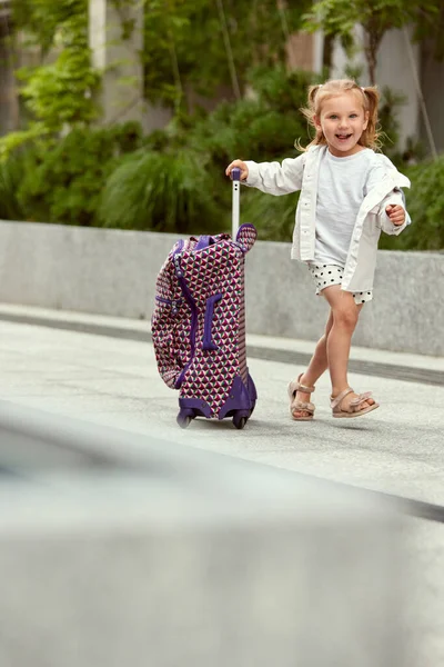 Ένα Χαμογελαστό Κορίτσι Ένα Παιδί Τραβάει Βαλίτσα Της Στο Δρόμο — Φωτογραφία Αρχείου