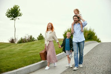 Güzel, sevgi dolu, genç bir aile, erkek ve kadın küçük oğulları ve kızlarıyla pikniğe gidiyorlar. Parkta sıcak bir yaz günü. Aile kavramı, çocukluk ve ebeveynlik, eğlence, hafta sonları, aşk, reklam