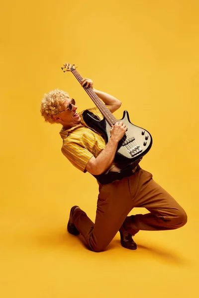 예술적 표현력 머리에 선글라스를 노란색 스튜디오 위에서 감정적으로 기타를 연주하는 — 스톡 사진