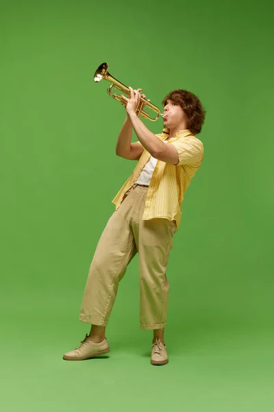 곱슬머리의 남자의 초상화 스튜디오 배경에 트럼펫을 연주하는 음악가 — 스톡 사진