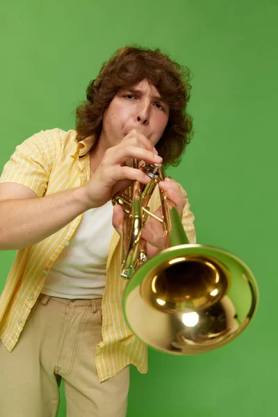 곱슬머리의 스튜디오 배경에 트럼펫을 연주하는 재능있는 음악가의 초상화 — 스톡 사진