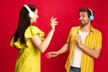 Parlak sarı elbiseli genç adam ve kadın kulaklıkla müzik dinliyor ve kırmızı stüdyo arka planında dans ediyorlar. Arkadaşlık kavramı, ilişki, iletişim, duygular, yaşam tarzı
