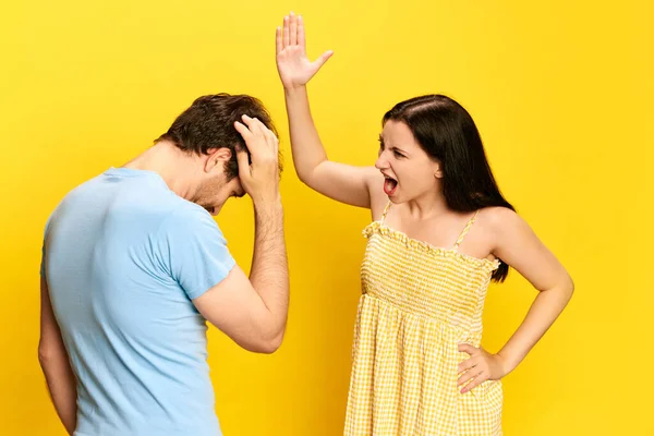 夫妻间的争吵 女人感情用事 对男人大喊大叫 抱怨工作室的黄色背景 生活方式 广告的概念 — 图库照片
