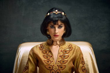 Çekici, ciddi bir genç kadının yakın plan portresi. Kraliçe Kleopatra 'nın görüntüsü. Koyu renkli arka planda kameraya bakıyor. Antik kültür kavramı, tarih, çağların karşılaştırması, sanat, reklam