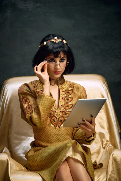 若い美しい女性の肖像画 暗いヴィンテージの背景に対してタブレットで座って黄金のドレスでクレオパトラ ビジネスレディー アンティーク文化 時代の比較 芸術の概念 — ストック写真