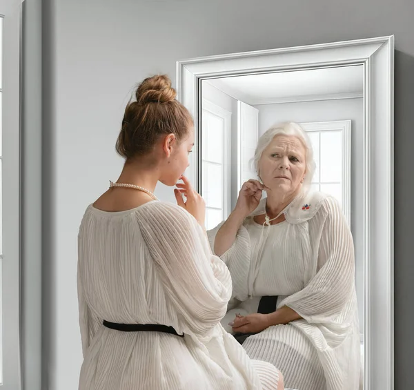 Creative conceptual collage. Young girl looking in mirror with older reflection of herself. Emotions and feelings. Look in future. Concept of present, past and future, age, lifestyle, generation, ad