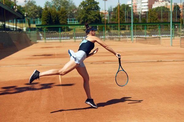 ゲーム中に運動中の集中女性テニス選手 晴れた日にオープンエアのコートでテニスをプレイ スポーツ アクティブなライフスタイル 持久力と強さの概念 — ストック写真
