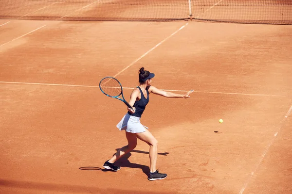 オープンエアのテニスコートでゲーム中の若い女性 運動中のテニス選手のトップビューイメージ ボールを出す スポーツ アクティブなライフスタイル 持久力と強さの概念 — ストック写真