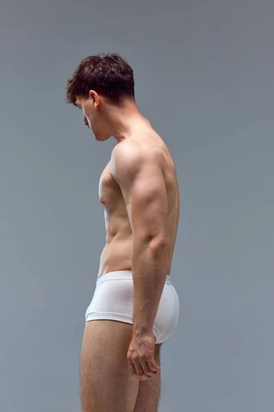 在灰色工作室背景下 年轻男子身穿内衣 身强体壮 赤身裸体的侧视图图像 救济之手 男人美的概念 运动健康的生活方式 运动的身体 — 图库照片