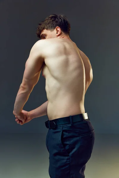 强壮的男人 肌肉发达 宽松的背对着灰色的工作室背景 穿着内衣 赤身裸体 男性美的概念 运动健康的生活方式 运动的身体 — 图库照片