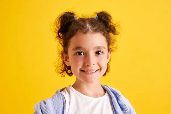 漂亮小女孩的特写 头发卷曲的孩子摆姿势 看着相机 在黄色的摄影棚背景下微笑 情感概念 生活方式 — 图库照片