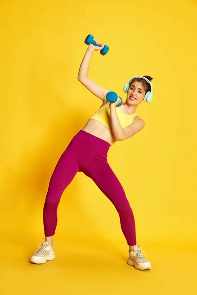 운동복을 노란색 스튜디오 배경에 무거운 반바지를 헤드폰 훈련을 모습이 스포츠 — 스톡 사진