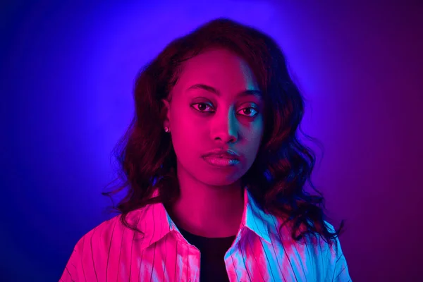在霓虹灯下 非洲女人在镜头前的特写 在渐变的蓝紫色工作室背景下摆姿势 人类情感 生活方式 广告的概念 — 图库照片