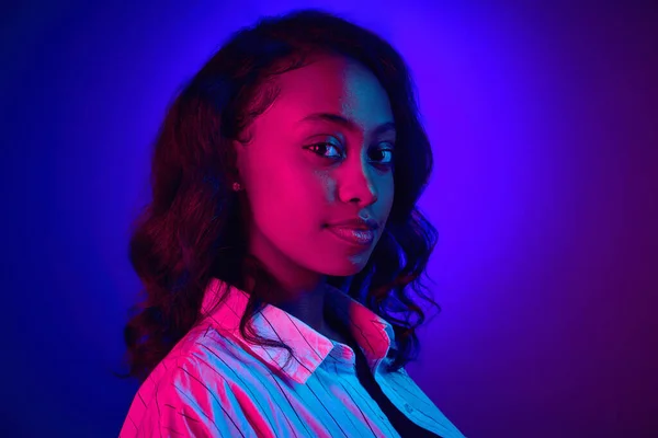 吸引人的非洲女人在镜头前的特写 在霓虹灯下与深蓝色紫色工作室背景相对照 人类情感 生活方式 广告的概念 — 图库照片
