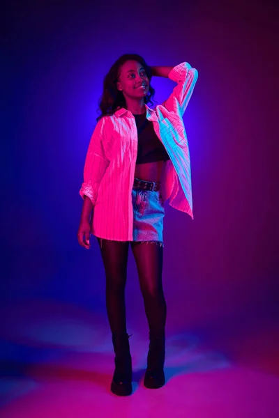 全长的肖像画 年轻的 非洲裔 美丽的女孩在霓虹灯下与渐变的蓝色紫色工作室背景相对照 人类情感 生活方式 广告的概念 — 图库照片