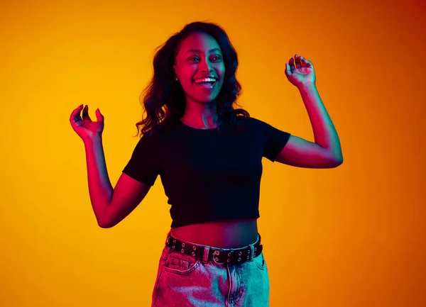 在霓虹灯下 年轻快乐而兴奋的非洲女人在黄色的工作室背景下微笑着 感到非常积极 人类情感 生活方式 广告的概念 — 图库照片