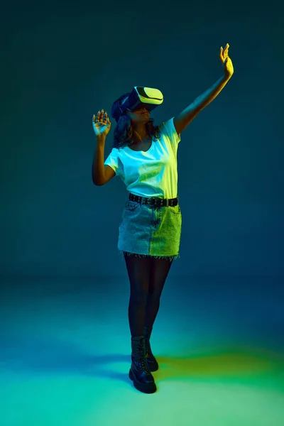 形象迷人的年轻非洲女子 身穿白色T恤 戴着Vr眼镜 在霓虹灯下的青色 蓝色的工作室背景 生活方式 广告的概念 — 图库照片