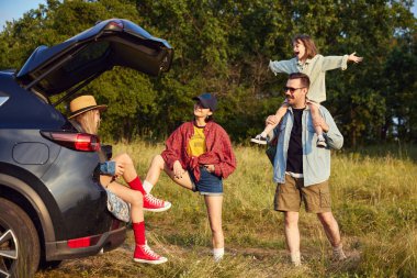 Pozitif erkek ve kadın, ebeveynler çocuklarıyla yürüyüşe çıkıyor. Sıcak yaz günü ve orman geçmişi. Boş zaman, eğlence, doğa, aktif yaşam tarzı, aile, seyahat kavramı