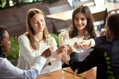 Neşeli gençler, iş çıkışı restoranda toplanan meslektaşlar, projeyi kutlamak, şampanya içmek ve konuşmak. Boş zaman, iş, iletişim, eğlence, alkol içeceği kavramı