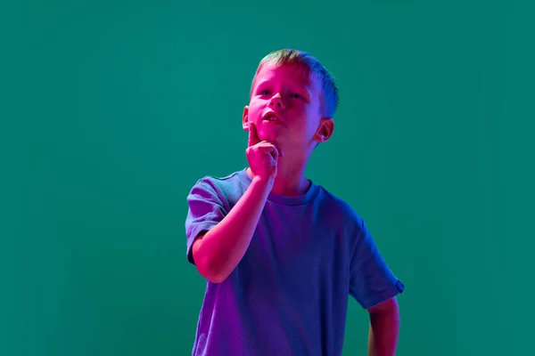 小聪明男孩的画像 站在霓虹灯下的青色画室背景下 脸上带着沉思的表情 童年的概念 生活方式 — 图库照片