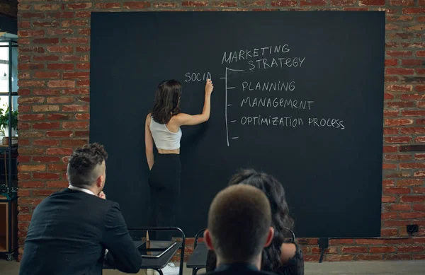 Junge Frau Wirtschaftslehrerin Die Der Tafel Über Marketinginstrumente Schreibt Treffen — Stockfoto