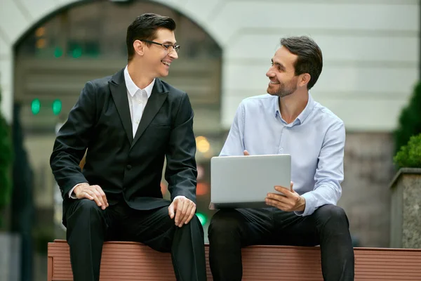 Cheerful Discussion Two Businessmen Coworkers Sitting Bench Office Looking Laptop — Stock Photo, Image
