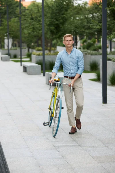 若いハンサムな男の完全な長さのイメージは スマートカジュアル服の従業員は初夏の朝に自転車で通りに沿って歩く ビジネス アクティブライフスタイル ファッション 生態学の概念 — ストック写真