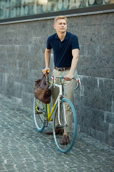 严肃的年轻人 办公室职员穿着漂亮的休闲装和公文包 骑着自行车站在街上 商业概念 积极的生活方式 — 图库照片