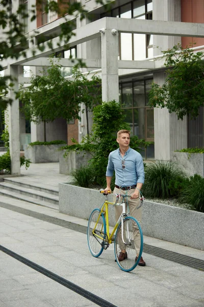若いハンサムなビジネスマンだ 自転車で屋外に立つスタイリッシュなスマートカジュアル服のオフィスワーカー 美しい都市の背景 ビジネス アクティブライフスタイル ファッション 生態学の概念 — ストック写真