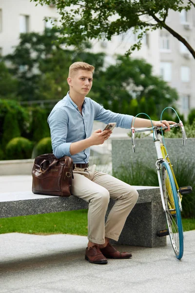 自転車でビーチに座って 携帯電話でオンラインで作業スマートカジュアル服でスタイリッシュな若いビジネスマン 都市の背景 ビジネス アクティブライフスタイル ファッション 生態学の概念 — ストック写真