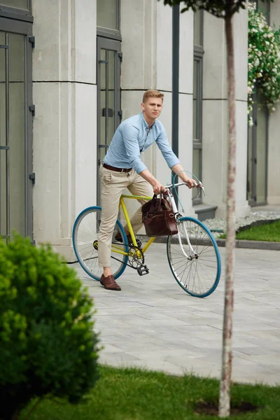 現代的な建物と街に沿って乗って 自転車に乗ってオフィスに行くスマートカジュアルな服でハンサムな エレガントなビジネスマン ビジネス アクティブライフスタイル ファッション 生態学の概念 — ストック写真